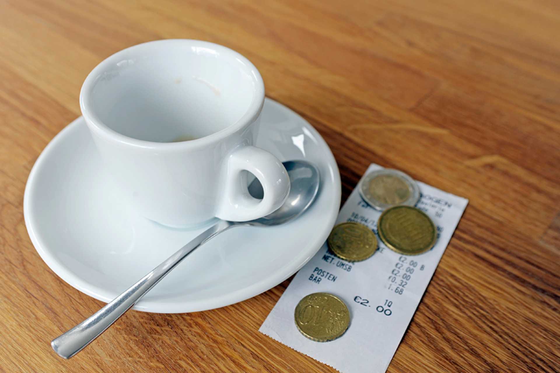 Kaffeetasse mit Rechnung und Münzen