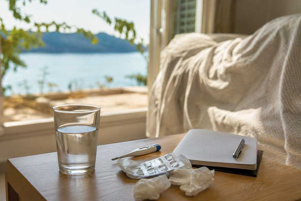 Krankentisch mit Wasserglas und Medikamenten