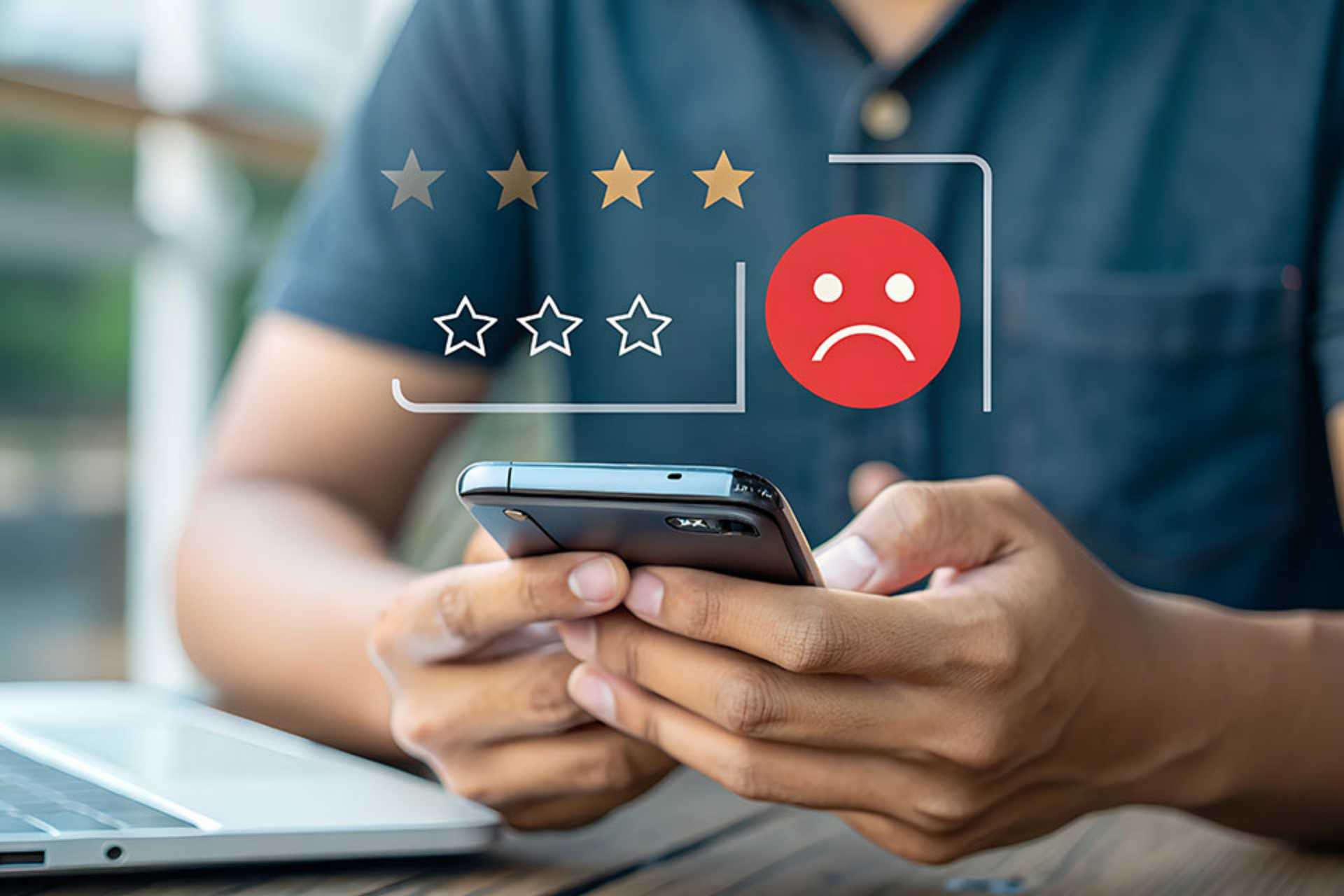 Mann bedient Smartphone, darüber negatives Smiley und schlechte Sterne Bewertung