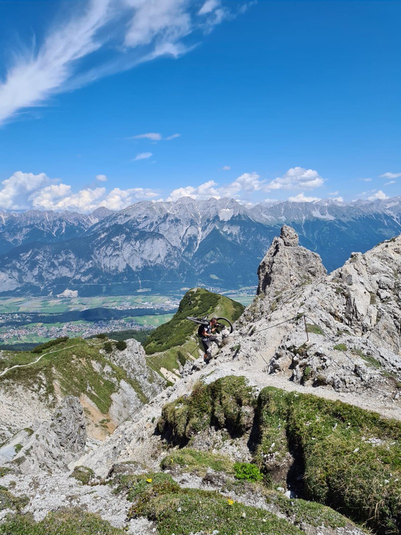 Mann geht mir seinem Rad auf dem Rücken einen Berg hinauf